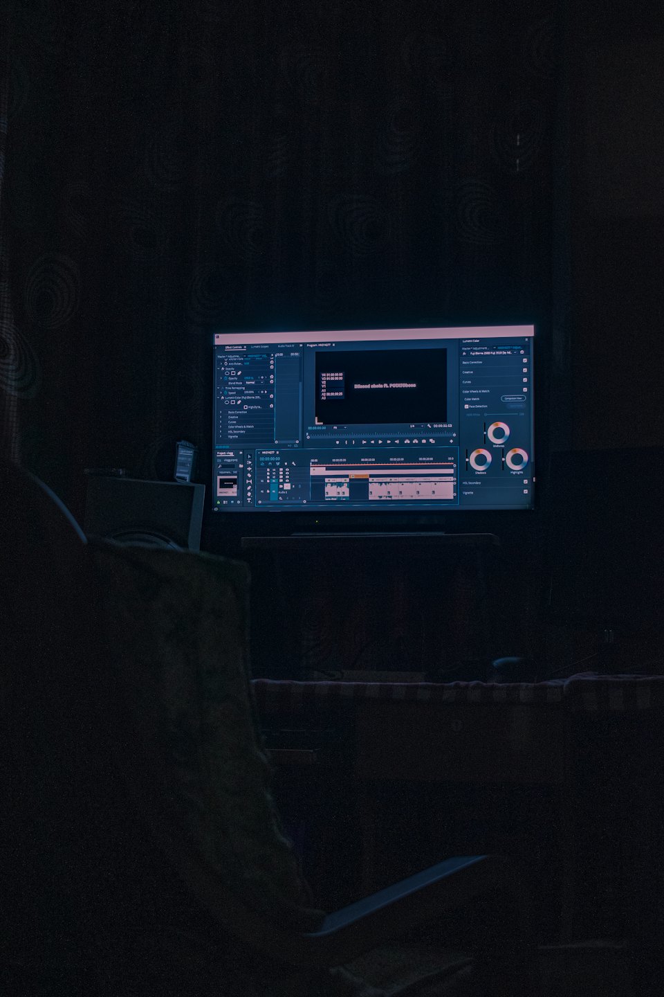 Computer monitor displaying video editing software in a dark room.